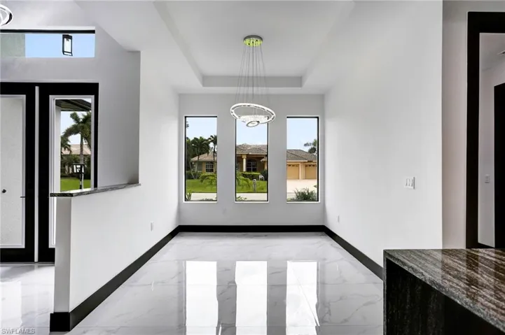 Unfurnished dining area with a tray ceiling and light tile patterned flooring