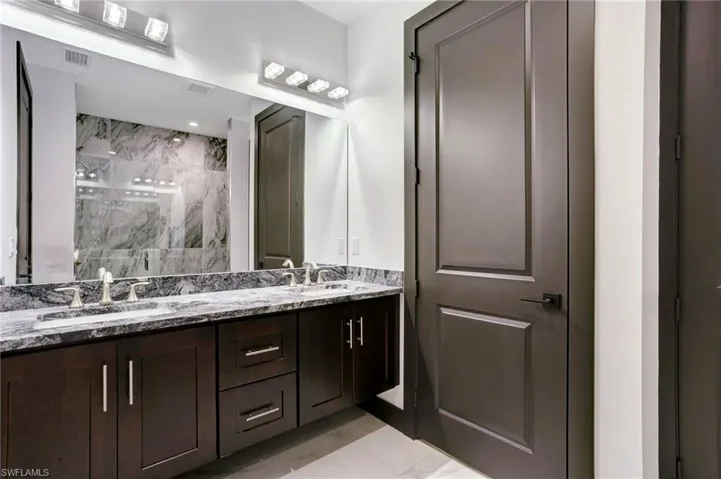 Bathroom featuring vanity, tiled shower, and tile patterned floors