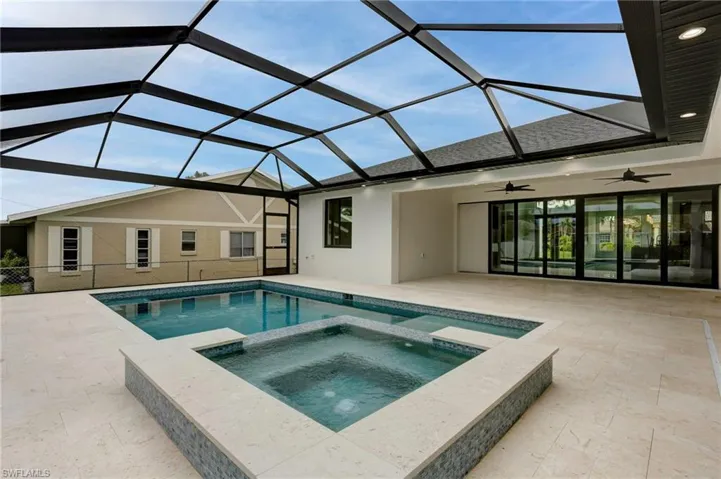 View of swimming pool with glass enclosure, an in ground hot tub, ceiling fan, and a patio area