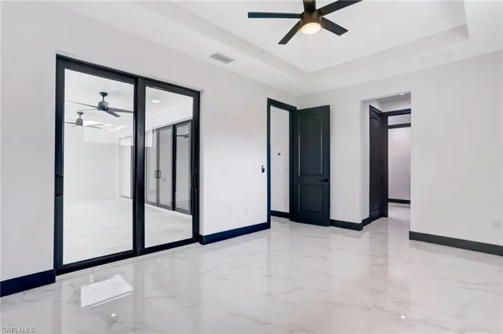 Unfurnished room with a raised ceiling, ceiling fan, and light tile patterned floors