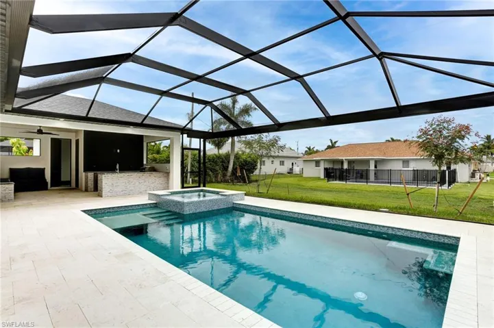 View of pool and heated spa. Outdoor kitchen in the background