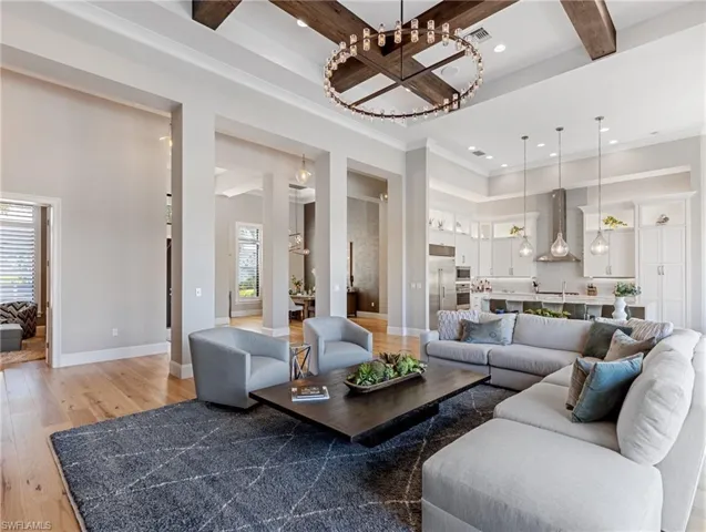 Living room featuring beam ceiling, hardwood  flooring, ornamental molding, and a high ceiling