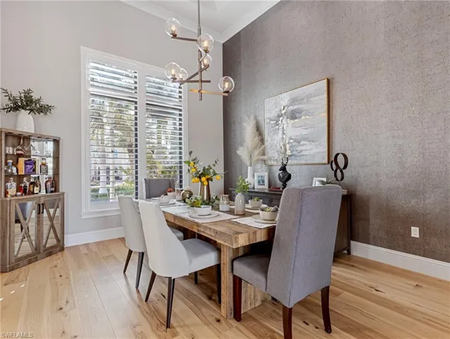 Dining area with a notable chandelier, ornamental molding, and light hardwood flooring