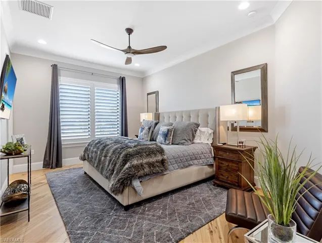 Bedroom with ceiling fan, crown molding, and wood-type flooring