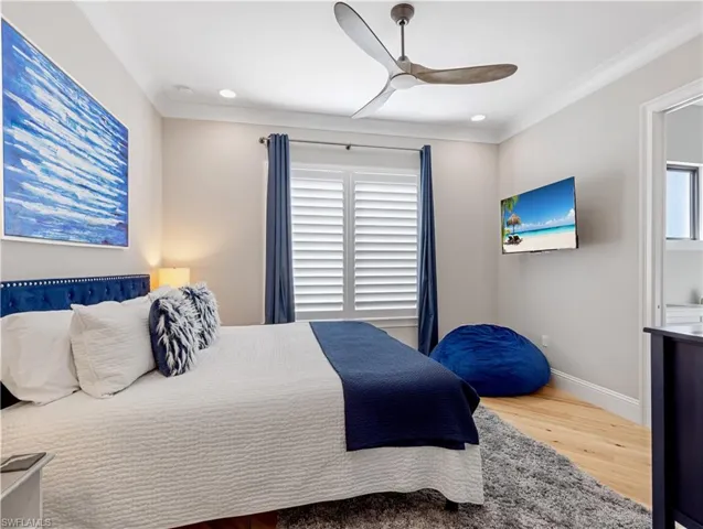 Bedroom with multiple windows, ceiling fan, wood-type flooring, and ornamental molding