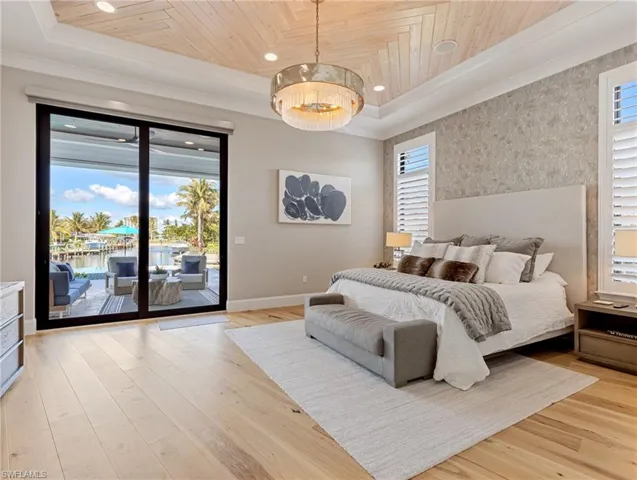 Bedroom with a raised ceiling, a notable chandelier, light hardwood / wood-style floors, access to outside, and wood ceiling