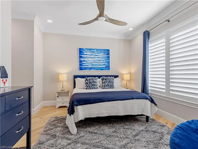 Bedroom with ceiling fan, light hardwood / wood-style flooring, and ornamental molding