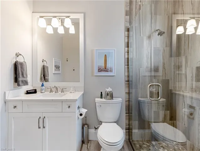 Bathroom featuring vanity, toilet, and a shower with door
