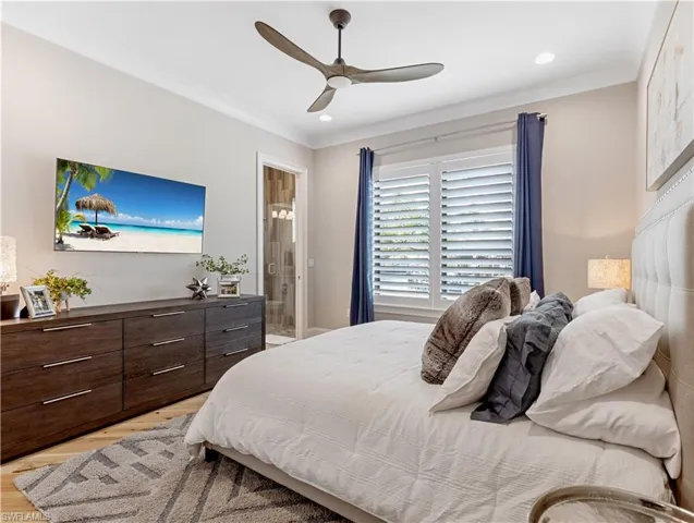 Bedroom featuring ceiling fan, ornamental molding, and ensuite bath