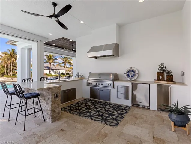 View of patio / terrace with exterior kitchen, ceiling fan, an outdoor bar, and grilling area