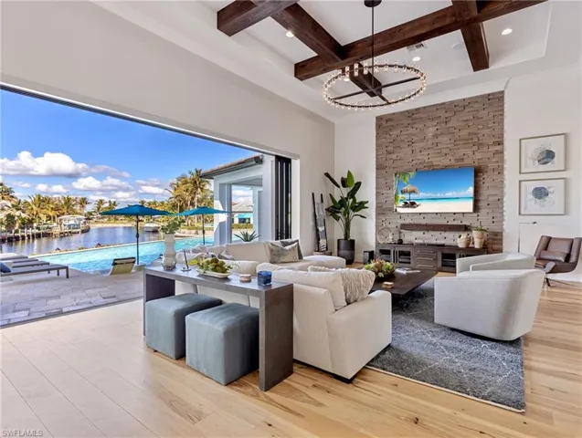 Living room featuring an inviting chandelier, coffered ceiling, a water view, light wood flooring, and beamed ceiling