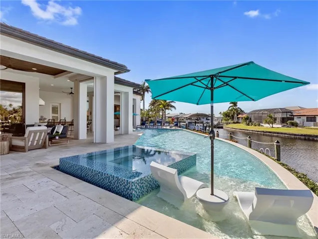 View of pool featuring ceiling fan, a patio area, a water view, and an in ground hot tub