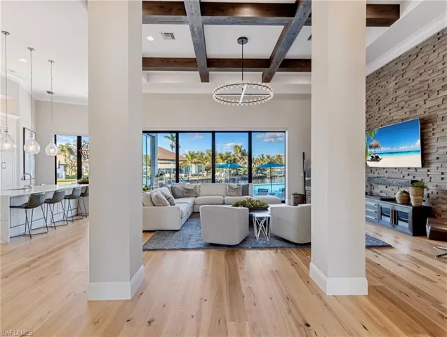 Living room featuring light hardwood flooring, beamed ceiling, coffered ceiling, and an inviting chandelier