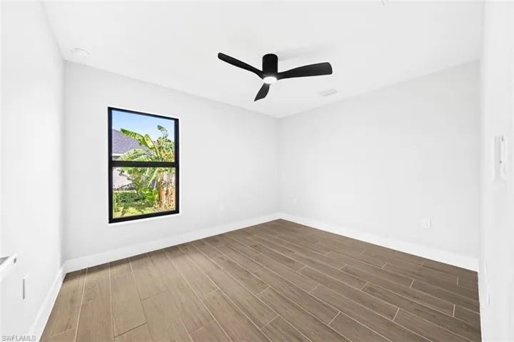 Room featuring wood-finish tile flooring, matte black ceiling fan with integrated lighting, and a single window with a black frame