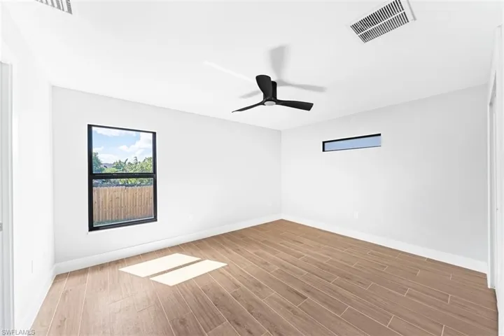 Neutral-toned interior featuring wood-finish tile flooring, matte black ceiling fan, and black-trimmed window frames