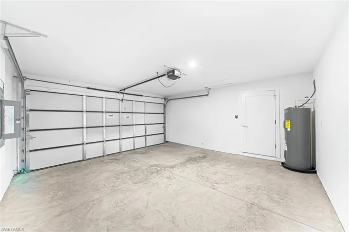 Attached garage featuring a multi-panel door with an automatic opener, finished concrete flooring, smooth wall surfaces, and a dedicated water heater