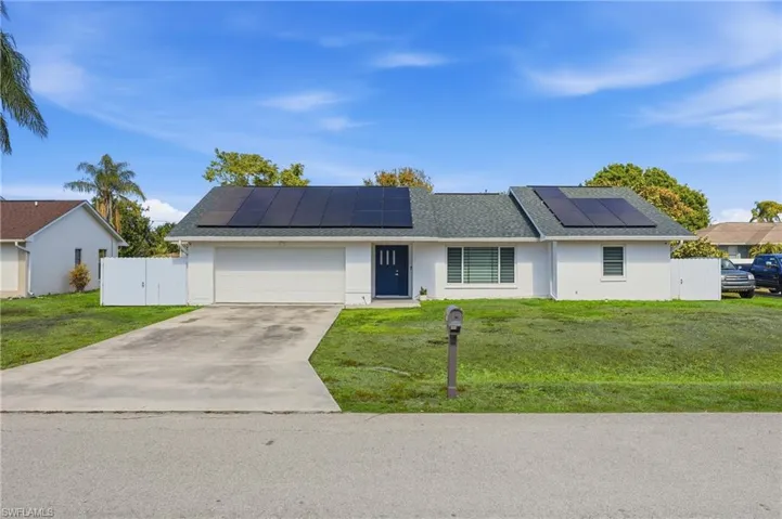Ranch-style home featuring a gate, solar panels, concrete driveway, stucco siding, and a shingled roof