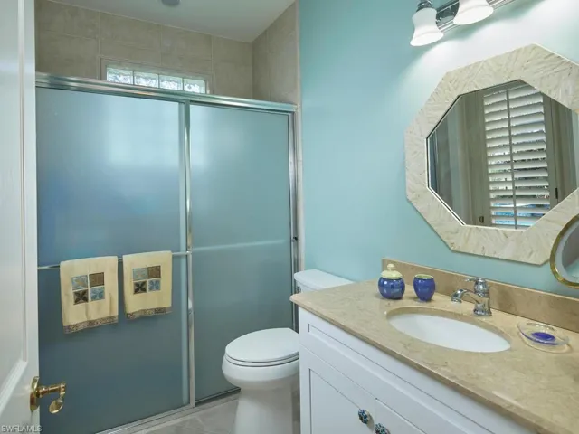 Bathroom featuring tile patterned flooring, a shower with door, vanity, and toilet