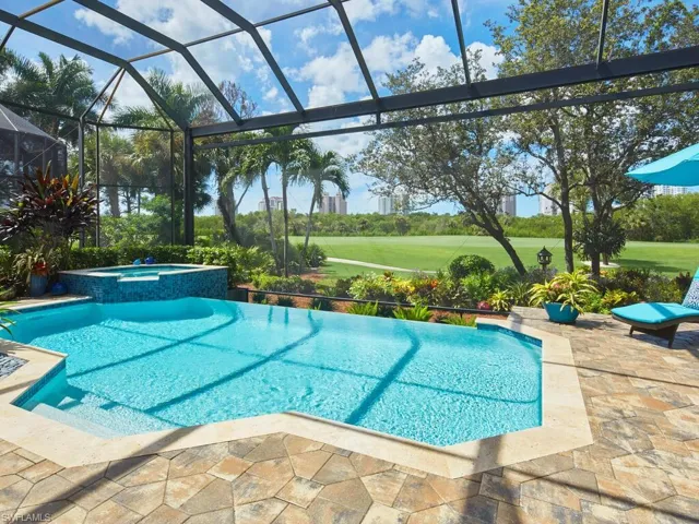 View of swimming pool featuring glass enclosure, an in ground hot tub, a yard, and a patio area