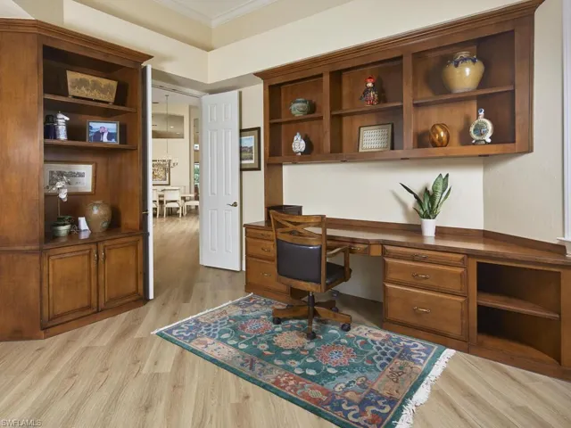 Office area with light hardwood / wood-style flooring, built in desk, and ornamental molding