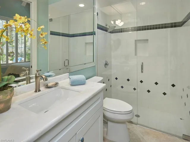 Bathroom featuring a shower with door, vanity, toilet, and a wealth of natural light