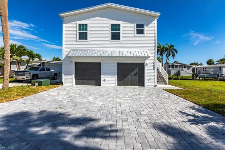 View of front of house featuring stairs, a front yard, decorative driveway, and a garage