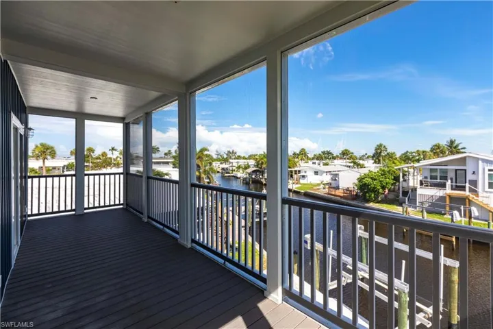 Unfurnished sunroom featuring a water view, a balcony, and a residential view