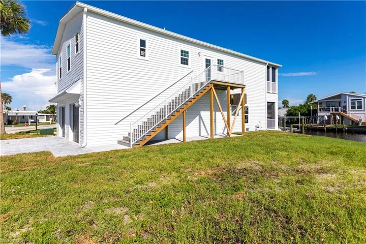 Rear view of property with a lawn, stairway, and decorative driveway