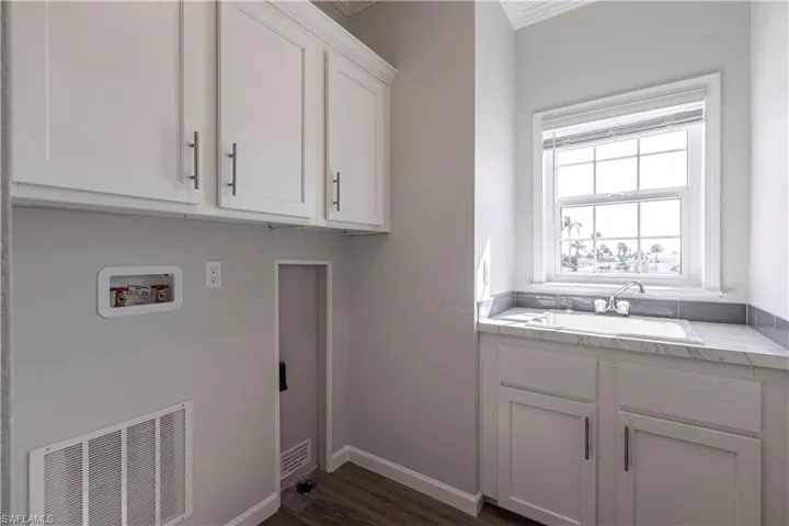 Washroom featuring cabinet space, dark wood-style flooring, hookup for a washing machine, and ornamental molding