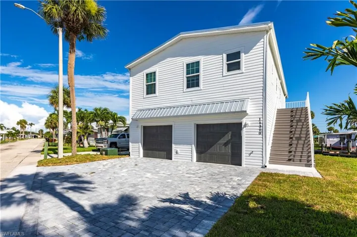 View of front facade featuring decorative driveway, a garage, a front lawn, and stairs