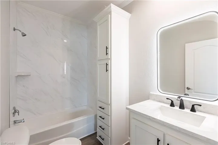 Bathroom featuring vanity, shower / bathtub combination, and crown molding