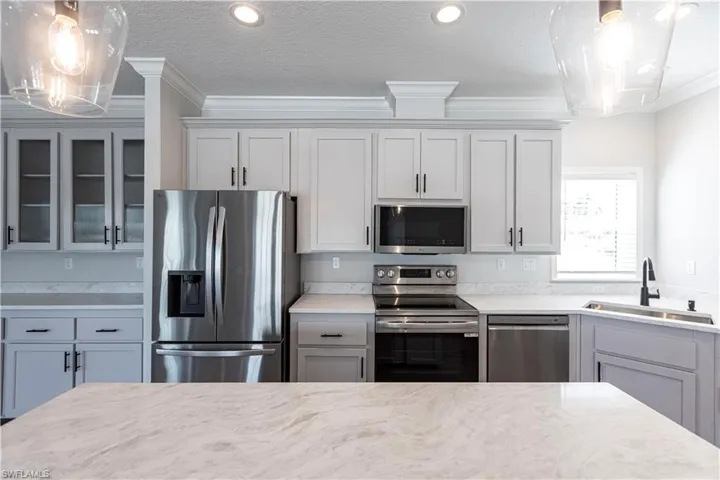 Kitchen featuring decorative light fixtures, stainless steel appliances, glass insert cabinets, a textured ceiling, and gray cabinets