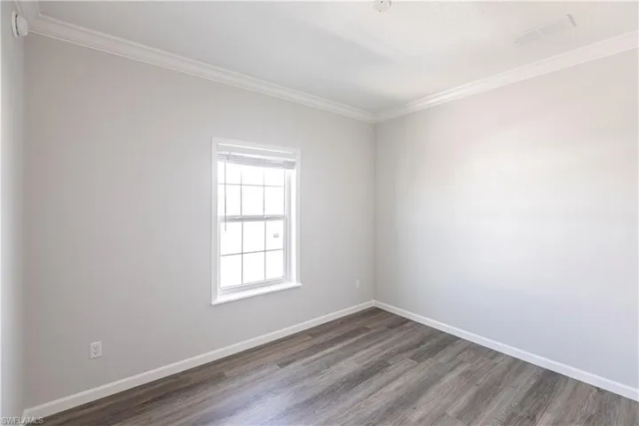 Spare room featuring crown molding and wood finished floors