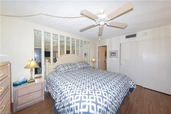 Bedroom featuring dark wood-type flooring, ceiling fan, a closet, and a textured ceiling