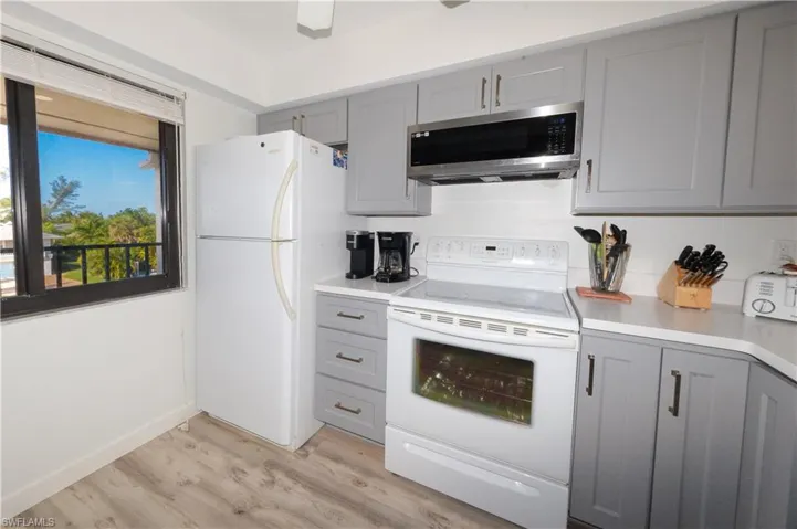 Kitchen featuring gray cabinetry, white appliances, and light countertops