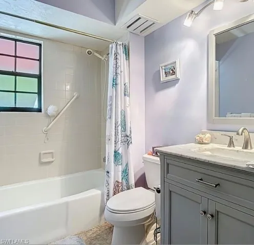 Bathroom featuring vanity and shower / bathtub combination with curtain