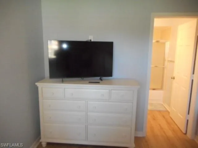 Bedroom with light wood-style flooring and connected bathroom