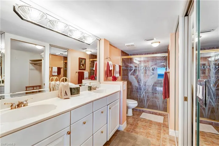 Bathroom with tile patterned floors, a shower with door, vanity, and toilet