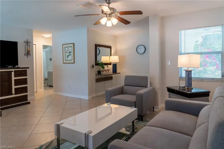 Living area with baseboards, a ceiling fan, visible vents, and light tile patterned floors