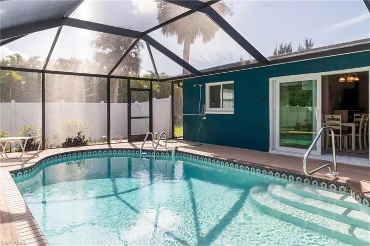 View of swimming pool featuring a fenced in pool, glass enclosure, fence, and a patio area