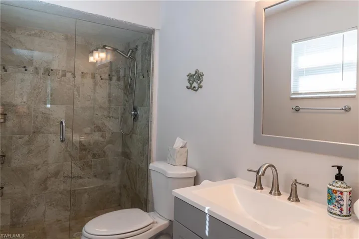 Full bathroom featuring a stall shower, toilet, and vanity