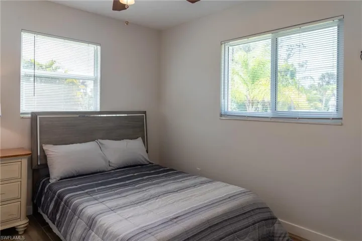 Bedroom with multiple windows, ceiling fan, and dark wood-style floors