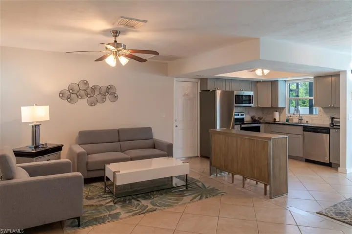 Living area featuring a ceiling fan, light tile patterned floors, and visible vents