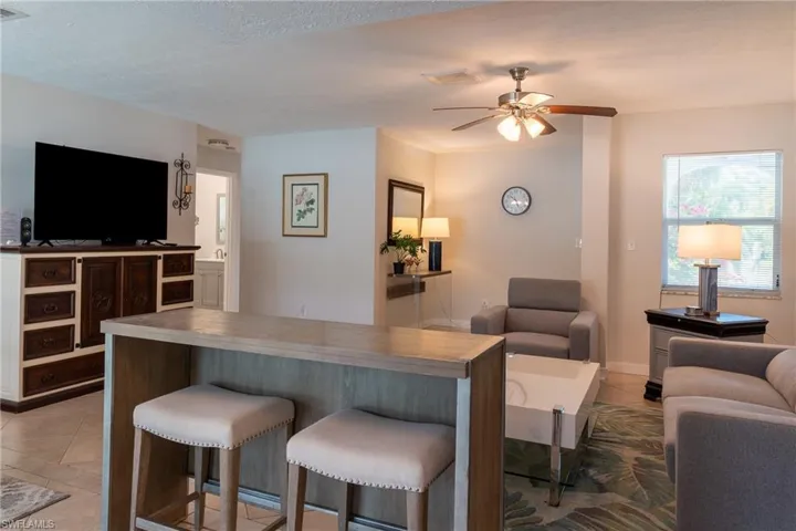 Living area with light tile patterned floors, visible vents, and ceiling fan