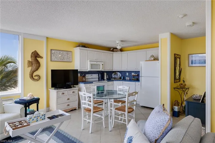 Kitchen featuring white cabinets, white appliances, tasteful backsplash, a textured ceiling, and light tile patterned flooring