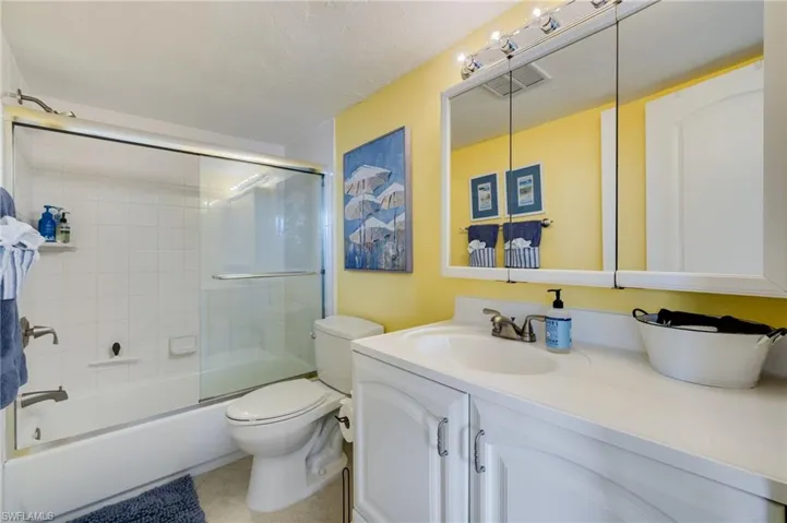 Bathroom with vanity, shower / bath combination with glass door, and light tile patterned flooring