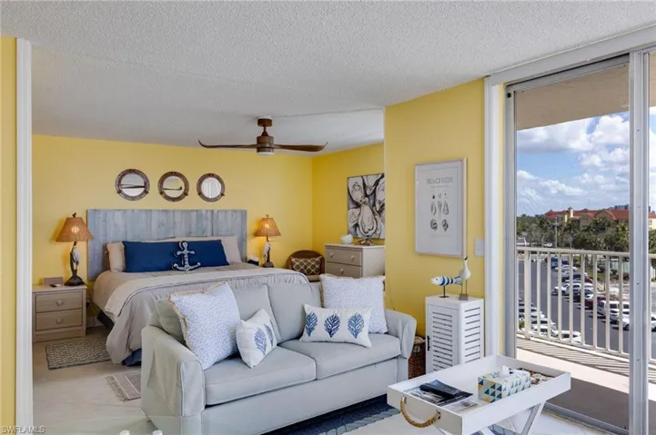 Tiled bedroom featuring access to exterior, a textured ceiling, a ceiling fan, and floor to ceiling windows