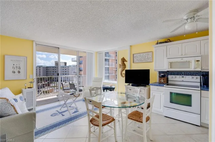 Kitchen featuring white appliances, floor to ceiling windows, white cabinets, a textured ceiling, and ceiling fan