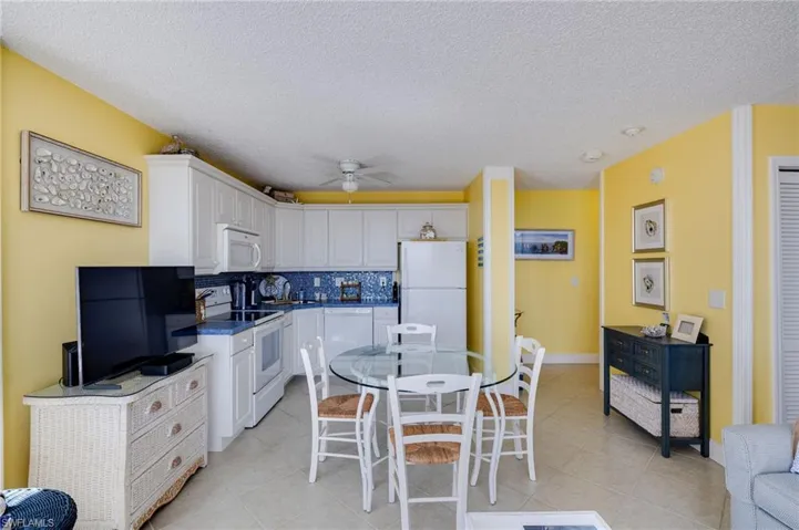 Kitchen featuring white appliances, white cabinetry, dark countertops, backsplash, and a textured ceiling