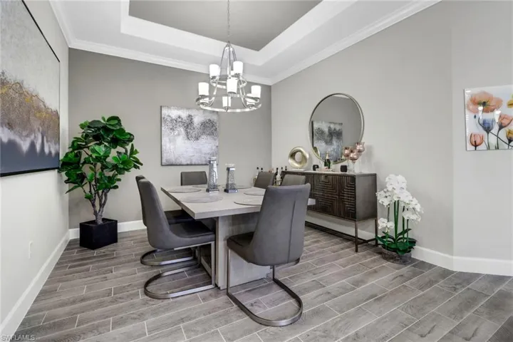 Dining space featuring wood tiled floors, suspended lighting, crown molding, and a raised ceiling